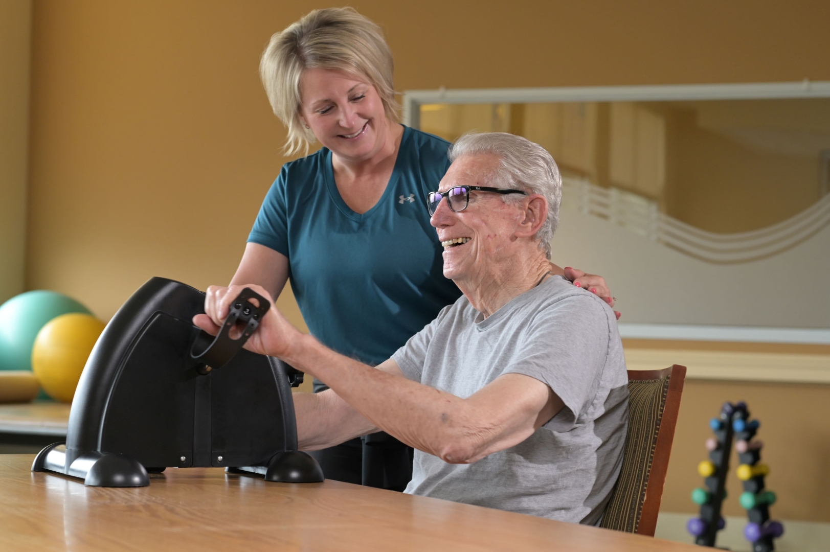 senior male using hand bike while working with a therapist